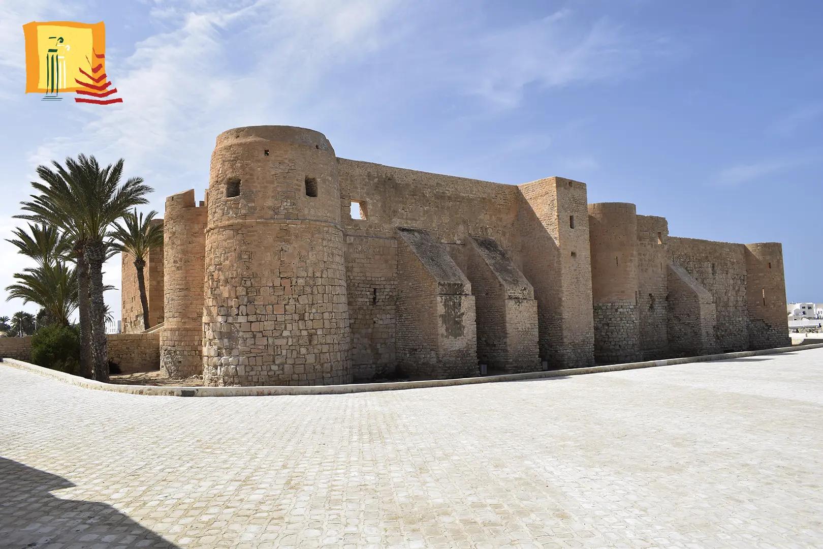 Mura in pietra del forte Ghazi Mustapha con torri rotonde e una palma a Houmt Souk Djerba