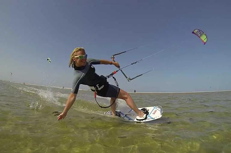 Kitesurfer in muta che scivola sulle acque turchesi dello spot di Sidi Yati a Djerba
